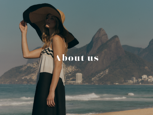 Set against an iconic coastal landscape, the image evokes a sense of freedom, identity, and effortless elegance. The model stands by the sea wearing a flowing, graphic dress and a wide-brimmed hat, framed by the contrast between natural beauty and urban horizon.

The scene reflects a lifestyle rooted in movement, authenticity, and connection to place — an invitation to discover the story, values, and spirit behind the brand.