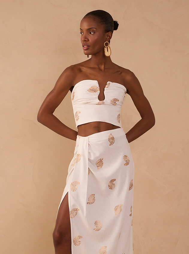 Woman wearing a white strapless crop top and wrap maxi skirt with gold leaf print, size S fashion model